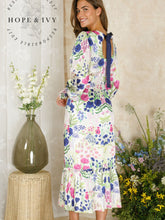 Load image into Gallery viewer, Hope & Ivy Caroline White Floral Maxi Dress – sustainable women’s satin floral print dress with blouson sleeves, frilled hem and tie-back detail. Ideal for weddings, garden parties and summer occasions.