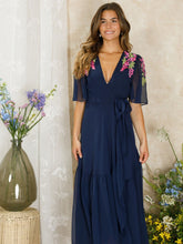 Load image into Gallery viewer, Hope & Ivy Grace navy embellished wrap dress with flutter sleeves, tie waist and pink/purple wisteria detail; maxi length approx. 143 cm.