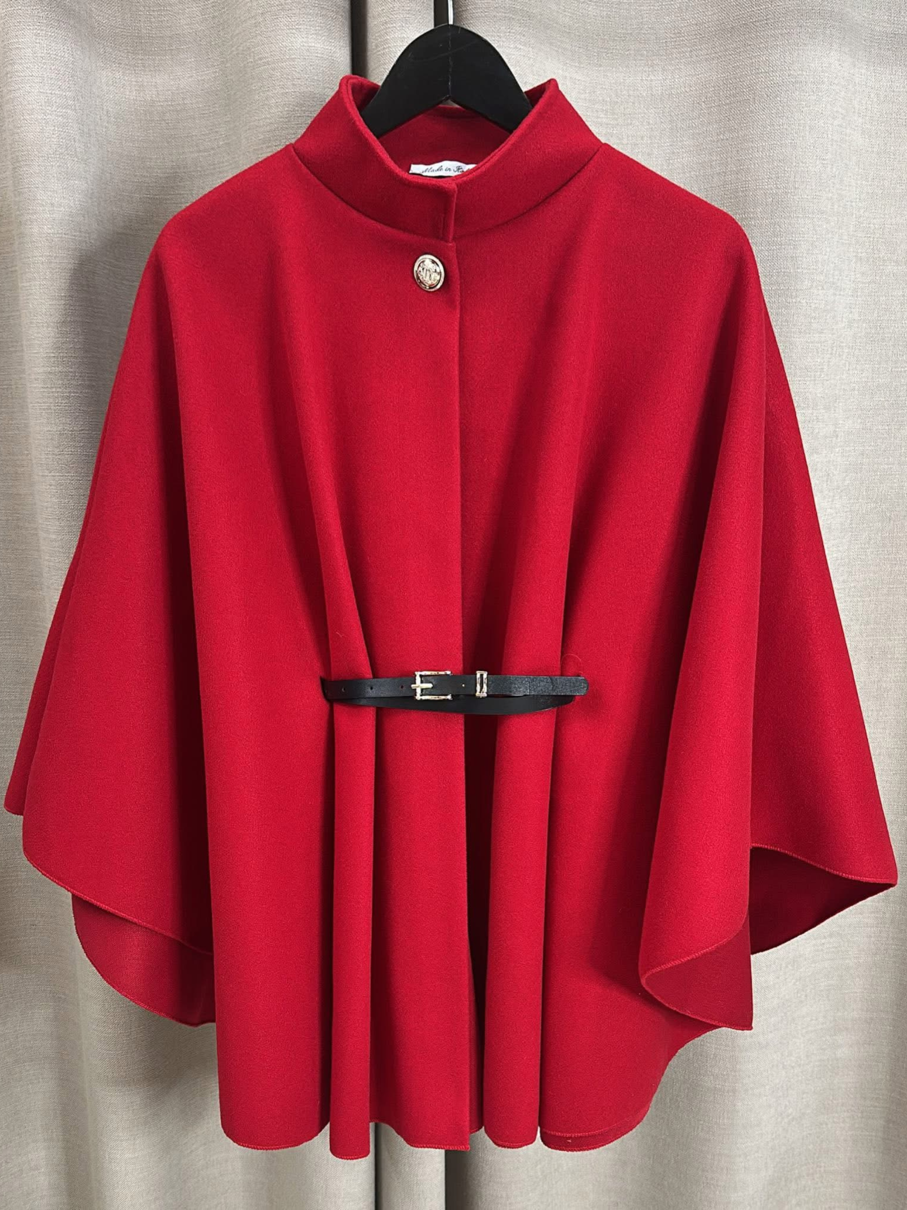 The QBAW25 RR Red Carrie Cape features a structured silhouette with wide sleeves, a high neckline and elegant gold button detailing. Finished with a detachable belt for a flattering fit, this chic cape blends timeless tailoring with modern sophistication - perfect for layering over seasonal outfits.