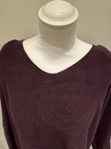The knit top features a relaxed silhouette, soft texture, and full-length sleeves in a deep mulberry hue, designed for effortless layering and cosy everyday wear.