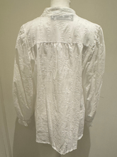 Load image into Gallery viewer, Deck by Decollage white embroidered cotton blouse featuring tonal script text, a split neckline, and ruffle cuffs. A breathable and elegant top ideal for smart-casual dressing.

