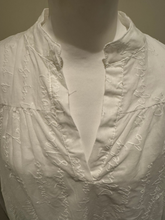 Load image into Gallery viewer, Deck by Decollage white embroidered cotton blouse featuring tonal script text, a split neckline, and ruffle cuffs. A breathable and elegant top ideal for smart-casual dressing.
