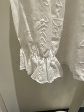 Load image into Gallery viewer, Deck by Decollage white embroidered cotton blouse featuring tonal script text, a split neckline, and ruffle cuffs. A breathable and elegant top ideal for smart-casual dressing.
