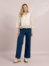 Load image into Gallery viewer, White sheer tie-front blouse with floral embroidery and 3/4 sleeves from Deck by Decollage, styled with dark trousers for a smart casual look.

