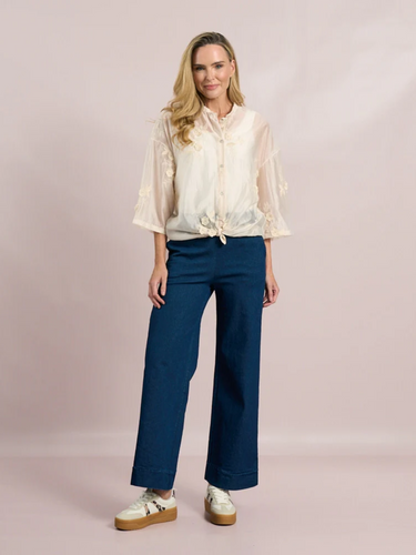 White sheer tie-front blouse with floral embroidery and 3/4 sleeves from Deck by Decollage, styled with dark trousers for a smart casual look.