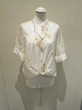 Load image into Gallery viewer, White sheer tie-front blouse with floral embroidery and 3/4 sleeves from Deck by Decollage, styled with dark trousers for a smart casual look.
