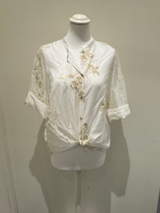 White sheer tie-front blouse with floral embroidery and 3/4 sleeves from Deck by Decollage, styled with dark trousers for a smart casual look.