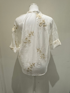 White sheer tie-front blouse with floral embroidery and 3/4 sleeves from Deck by Decollage, styled with dark trousers for a smart casual look.