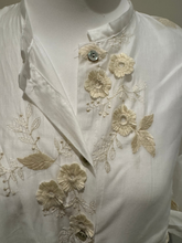 Load image into Gallery viewer, White sheer tie-front blouse with floral embroidery and 3/4 sleeves from Deck by Decollage, styled with dark trousers for a smart casual look.
