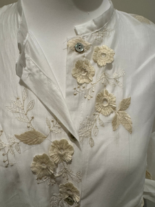 White sheer tie-front blouse with floral embroidery and 3/4 sleeves from Deck by Decollage, styled with dark trousers for a smart casual look.