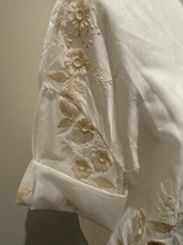Load image into Gallery viewer, White sheer tie-front blouse with floral embroidery and 3/4 sleeves from Deck by Decollage, styled with dark trousers for a smart casual look.

