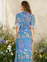 Load image into Gallery viewer, Hope &amp; Ivy Avaline Floral Frill Trim Maxi Wrap Dress – women’s blue floral wrap dress with frilled hem and flutter sleeves. Hand-designed print with tie waist. Perfect for weddings, garden parties, and special occasions.
