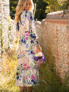 Hope & Ivy Caroline White Floral Maxi Dress – sustainable women’s satin floral print dress with blouson sleeves, frilled hem and tie-back detail. Ideal for weddings, garden parties and summer occasions.