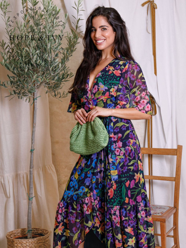 Hope & Ivy Nesta Floral Wrap Dress – sustainable navy floral chiffon wrap dress with flutter sleeves and tie waist. Made from 100% recycled materials. Perfect for weddings, garden parties, and summer occasions.