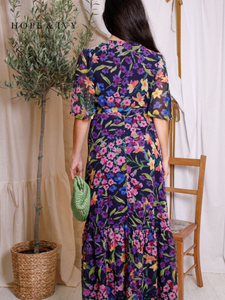 Hope & Ivy Nesta Floral Wrap Dress – sustainable navy floral chiffon wrap dress with flutter sleeves and tie waist. Made from 100% recycled materials. Perfect for weddings, garden parties, and summer occasions.