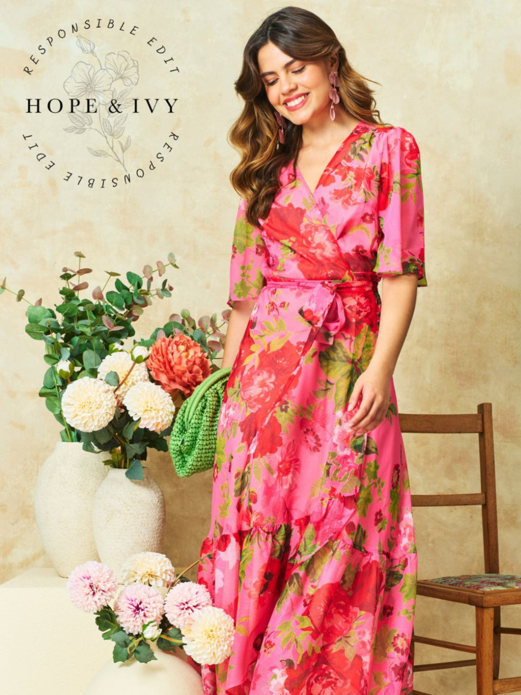 Hope & Ivy Roxanne Floral Dress – sustainable pink floral maxi wrap dress with flutter sleeves and tie waist. Hand-painted red floral design made from 100% recycled materials. Perfect for weddings and summer occasions.