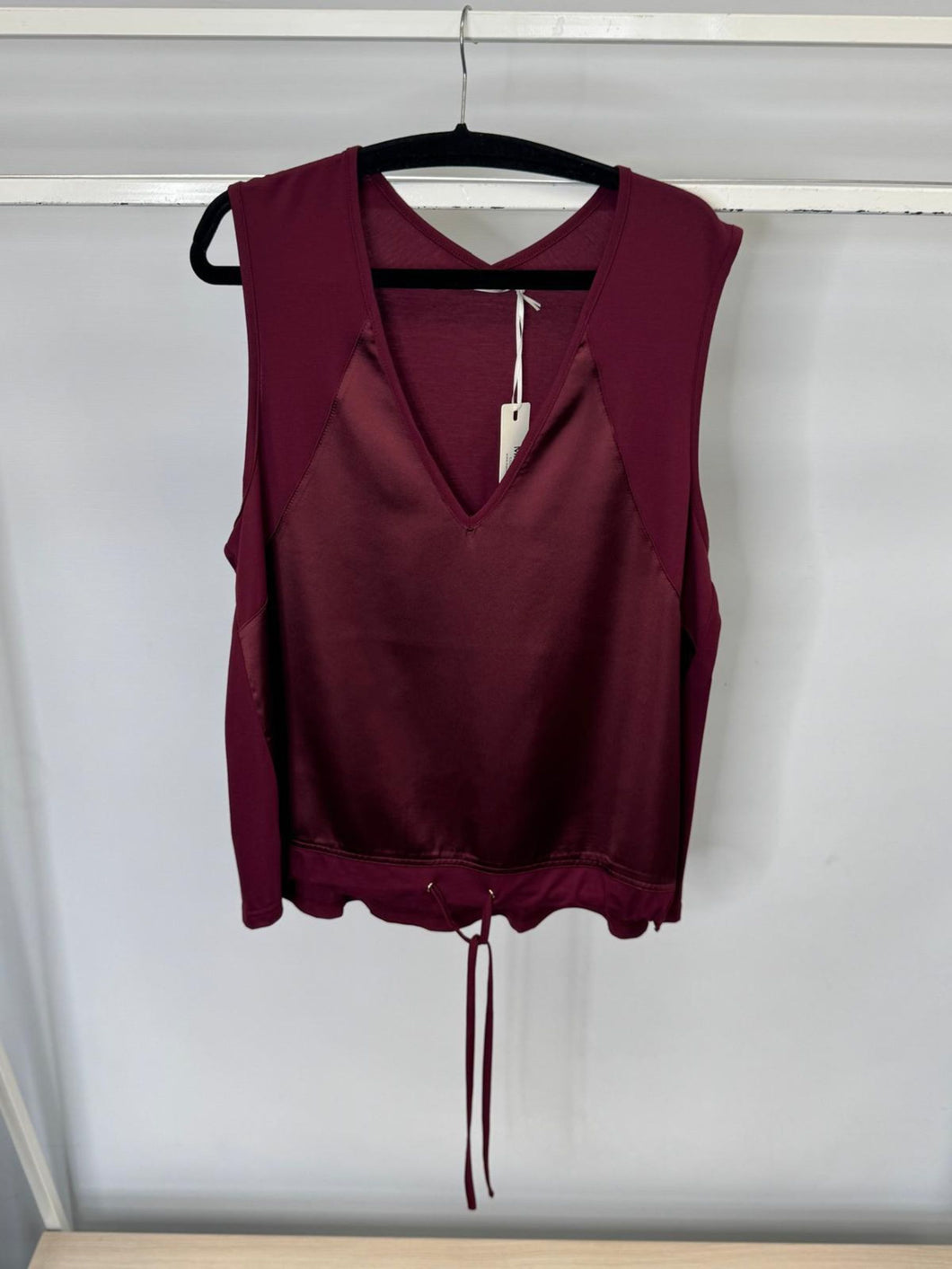 Maroon sleeveless top on a hanger against a white background