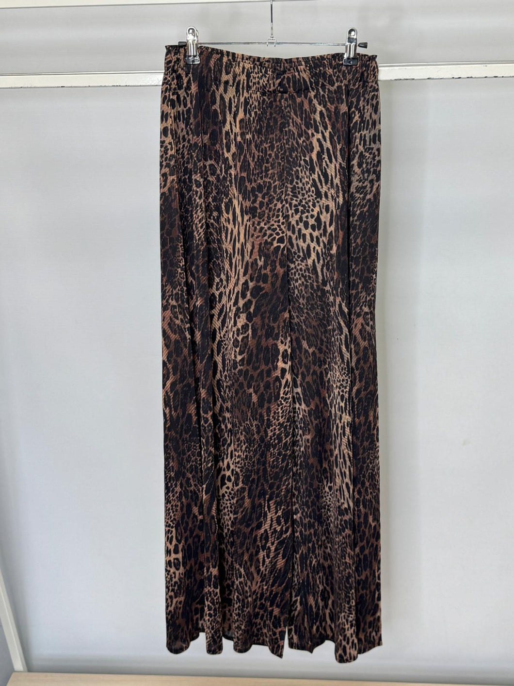 Leopard print trousers hanging on a rack against a white background