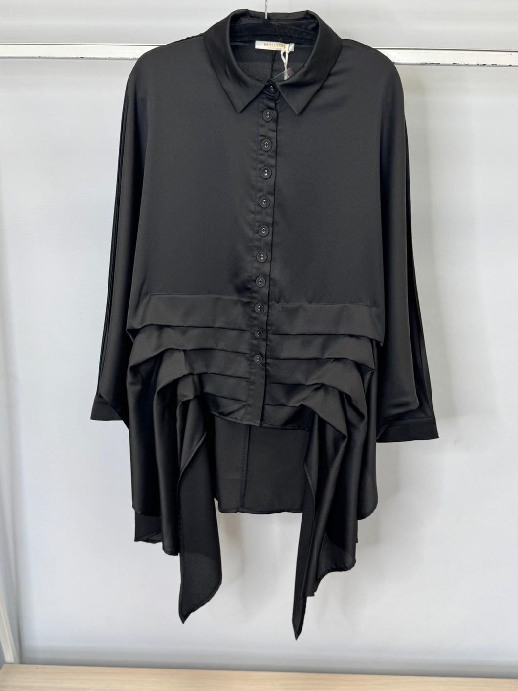 Black layered shirt on a hanger against a white background