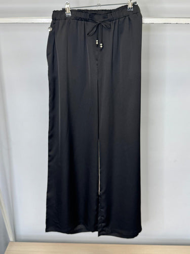 Black pants hanging on a rack against a white background