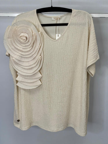 Beige top with floral embellishment on a hanger against a gray background