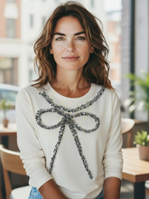 Load image into Gallery viewer, Malissa J WF2503 winter white sequin bow top—women’s embellished long-sleeve jersey top with silver bow detail.

