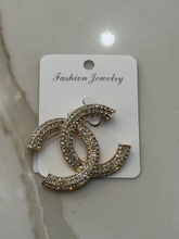 Load image into Gallery viewer, Nouvelle CC Brooch Gold – luxury women’s crystal brooch with double C design, gold-tone finish and sparkling rhinestones. Perfect statement accessory for blazers, scarves and evening wear.
