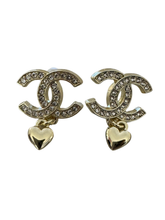 Load image into Gallery viewer, Nouvelle CC Gold Earrings featuring crystal-embellished interlocking design with a dangling gold heart charm, perfect for adding sparkle and elegance to any outfit.
