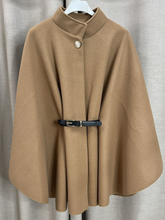 Load image into Gallery viewer, The QBAW25 RR Camel Carrie Cape features a structured silhouette with wide sleeves, a high neckline and elegant gold button detailing. Finished with a detachable belt for a flattering fit, this chic cape blends timeless tailoring with modern sophistication - perfect for layering over seasonal outfits.
