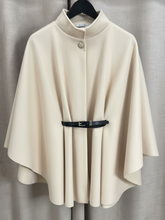 Load image into Gallery viewer, The QBAW25 RR Cream Carrie Cape features a structured silhouette with wide sleeves, a high neckline and elegant gold button detailing. Finished with a detachable belt for a flattering fit, this chic cape blends timeless tailoring with modern sophistication - perfect for layering over seasonal outfits.
