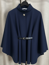 Load image into Gallery viewer, The QBAW25 RR Navy Carrie Cape features a structured silhouette with wide sleeves, a high neckline and elegant gold button detailing. Finished with a detachable belt for a flattering fit, this chic cape blends timeless tailoring with modern sophistication - perfect for layering over seasonal outfits.
