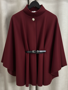 The QBAW25 RR Wine Carrie Cape features a structured silhouette with wide sleeves, a high neckline and elegant gold button detailing. Finished with a detachable belt for a flattering fit, this chic cape blends timeless tailoring with modern sophistication - perfect for layering over seasonal outfits.